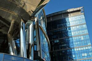 Glass building with transparent facade of the building and blue sky. Structural glass wall reflecting blue sky. Abstract modern architecture fragment. Contemporary architectural background. photo