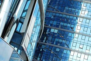 Glass building with transparent facade of the building and blue sky. Structural glass wall reflecting blue sky. Abstract modern architecture fragment. Contemporary architectural background. photo