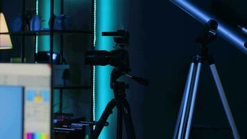 Professional camera equipment in empty blue neon lit creative photography studio. Video production gear in multimedia agency office specialized in post production editing