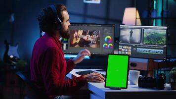 vídeo editor acrescenta som efeitos para filmado imagens de vídeo, trabalhando dentro postar Produção estúdio com verde tela tábua. cinegrafista usando fones de ouvido para teste e melhorar audio qualidade Próximo para brincar dispositivo video