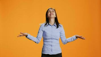 Spiritual woman praying to Jesus in front of orange background, presenting her gratitude to God during prayer session. Asian person showing belief and faith in religion, asking for peace. video