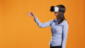 Asian woman operates virtual reality headset on camera, enjoying metaverse artificial intelligence on modern goggles. Young person using vr glasses for visual tech simulation in studio. video