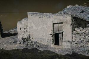 a house in the desert with a stone wall photo