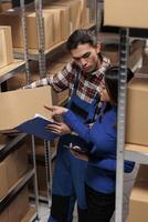 Warehouse managers taking parcel from shelf and checking code on digital tablet. Retail storehouse asian coworkers managing customer order picking, packing and shipping in storage room photo