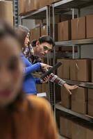 Warehouse employees inspecting parcels on rack and doing inventory management. Storehouse asian package handler and supervisor checking goods maintenance on shelf in storage room photo