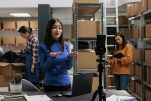 Postal service warehouse worker recording explainer video on mobile phone about parcel dispatching management. Post office storehouse manager streaming delivery manager working in storage photo