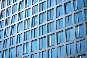 Glass building with transparent facade of the building and blue sky. Structural glass wall reflecting blue sky. Abstract modern architecture fragment. Contemporary architectural background. photo