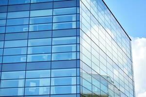 Glass building with transparent facade of the building and blue sky. Structural glass wall reflecting blue sky. Abstract modern architecture fragment. Contemporary architectural background. photo