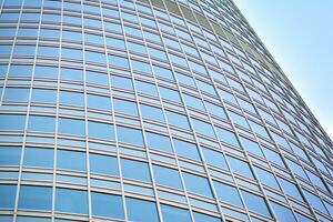 Glass building with transparent facade of the building and blue sky. Structural glass wall reflecting blue sky. Abstract modern architecture fragment. Contemporary architectural background. photo