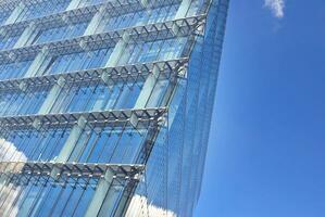 Glass building with transparent facade of the building and blue sky. Structural glass wall reflecting blue sky. Abstract modern architecture fragment. Contemporary architectural background. photo