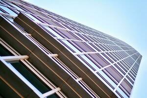 Glass building with transparent facade of the building and blue sky. Structural glass wall reflecting blue sky. Abstract modern architecture fragment. Contemporary architectural background. photo