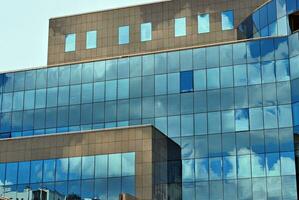Glass building with transparent facade of the building and blue sky. Structural glass wall reflecting blue sky. Abstract modern architecture fragment. Contemporary architectural background. photo