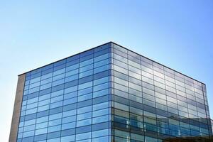 Glass building with transparent facade of the building and blue sky. Structural glass wall reflecting blue sky. Abstract modern architecture fragment. Contemporary architectural background. photo