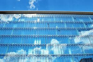 Glass building with transparent facade of the building and blue sky. Structural glass wall reflecting blue sky. Abstract modern architecture fragment. Contemporary architectural background. photo