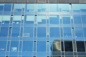 Glass building with transparent facade of the building and blue sky. Structural glass wall reflecting blue sky. Abstract modern architecture fragment. Contemporary architectural background. photo