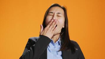 Exhausted person in formal clothes yawning and feeling sleepy in studio, trying to be awake and not fall asleep on camera. Young asian woman being tired and stressed, expressing burnout. video