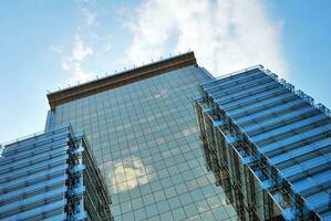 Glass building with transparent facade of the building and blue sky. Structural glass wall reflecting blue sky. Abstract modern architecture fragment. Contemporary architectural background. photo