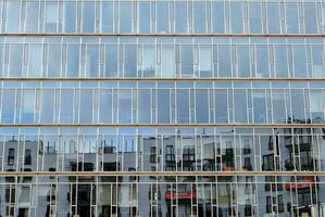 Glass building with transparent facade of the building and blue sky. Structural glass wall reflecting blue sky. Abstract modern architecture fragment. Contemporary architectural background. photo