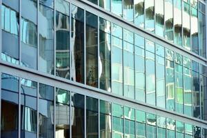 Glass building with transparent facade of the building and blue sky. Structural glass wall reflecting blue sky. Abstract modern architecture fragment. Contemporary architectural background. photo