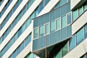 Glass building with transparent facade of the building and blue sky. Structural glass wall reflecting blue sky. Abstract modern architecture fragment. Contemporary architectural background. photo