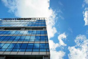 vaso edificio con transparente fachada de el edificio y azul cielo. estructural vaso pared reflejando azul cielo. foto