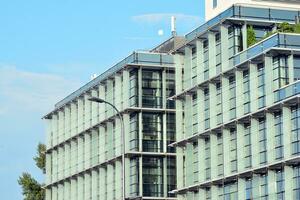 Glass building with transparent facade of the building and blue sky. Structural glass wall reflecting blue sky. Abstract modern architecture fragment. Contemporary architectural background. photo