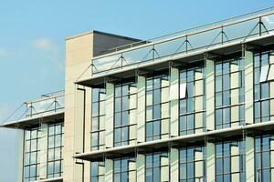 Glass building with transparent facade of the building and blue sky. Structural glass wall reflecting blue sky. Abstract modern architecture fragment. Contemporary architectural background. photo