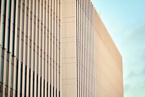 Glass building with transparent facade of the building and blue sky. Structural glass wall reflecting blue sky. Abstract modern architecture fragment. Contemporary architectural background. photo