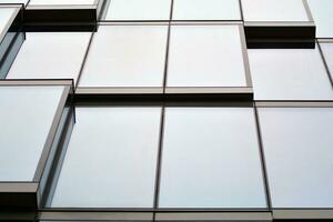 Glass building with transparent facade of the building and blue sky. Structural glass wall reflecting blue sky. Abstract modern architecture fragment. Contemporary architectural background. photo