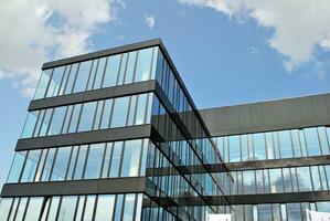 Glass building with transparent facade of the building and blue sky. Structural glass wall reflecting blue sky. Abstract modern architecture fragment. Contemporary architectural background. photo