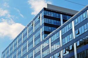Glass building with transparent facade of the building and blue sky. Structural glass wall reflecting blue sky. Abstract modern architecture fragment. Contemporary architectural background. photo