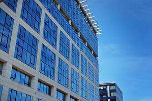 Glass building with transparent facade of the building and blue sky. Structural glass wall reflecting blue sky. Abstract modern architecture fragment. Contemporary architectural background. photo