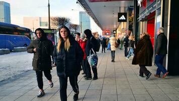 Warsaw, Poland. 5 December 2023. Residents and guests walk along the central street of city. People on sidewalk on with shops. photo