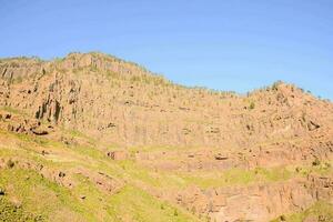 a mountain with a rocky face and a blue sky photo