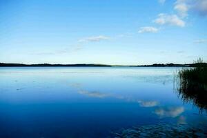 a lake with a blue sky and clouds reflected in it photo