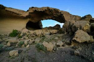 a rock formation in the desert with a large arch photo