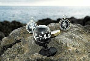 compasses on a rock near the ocean photo