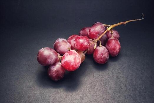 A sprig of grapes or vitis vinifera fruits was photographed with the concept of giving a light effect to the grapes isolated on black background. photo