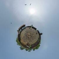 coconut trees in jungle in Indian tropic village on sea shore with fisher boat on little planet in evening sky, transformation of spherical 360 panorama. photo