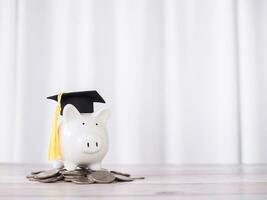Piggy bank with graduation hat on stack of coins. The concept of saving money for education, student loan, scholarship, tuition fees in future photo