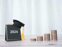 estudiar objetivos, 2024 escritorio calendario con graduación sombrero y apilar de monedas el concepto de ahorro dinero para educación, estudiante préstamo, beca, matrícula Tarifa en nuevo año 2024 foto