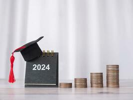 estudiar objetivos, 2024 escritorio calendario con graduación sombrero y apilar de monedas el concepto de ahorro dinero para educación, estudiante préstamo, beca, matrícula Tarifa en nuevo año 2024 foto