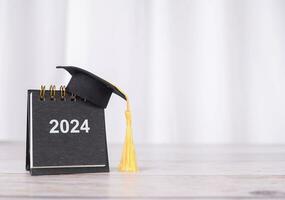 Study goals, 2024 Desk calendar with graduation hat. The concept for Resolution, Goal, Action, Planning, and manage time to success graduate. photo