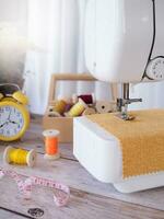 Close up sewing machine working with yellow fabric, sewing accessories on the table, stitch new clothing. photo