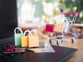 Shopping bags and credit cards on a laptop keyboard with Paper shopping bags in a trolley. The concepts about Business E-Commerce and online shopping that offers home delivery photo