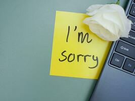 Top view of words i'm sorry written on sticky note on laptop keyboard with roses photo