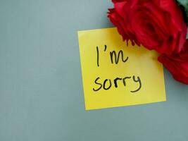 Top view of words i'm sorry written on sticky note with roses photo