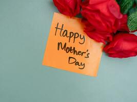 Top view of words happy mother's day written on sticky note with roses. Greetings for Mother's Day photo