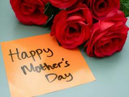 Top view of words happy mother's day written on sticky note with roses. Greetings for Mother's Day photo