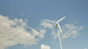 uno blanco molino en azul cielo y nubes fondo, giro en viento a generar limpiar eléctrico energía industria, natural poder recurso tecnología para sostenible ecología y ambiente conservación. foto